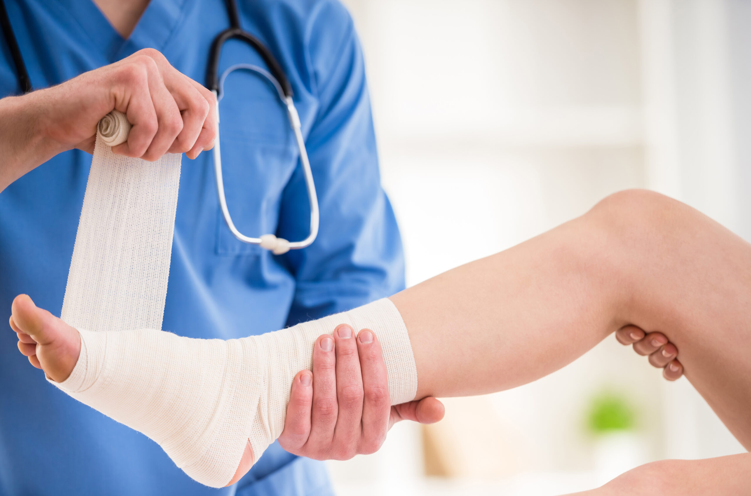Close-up,Of,Male,Doctor,Bandaging,Foot,Of,Female,Patient,At